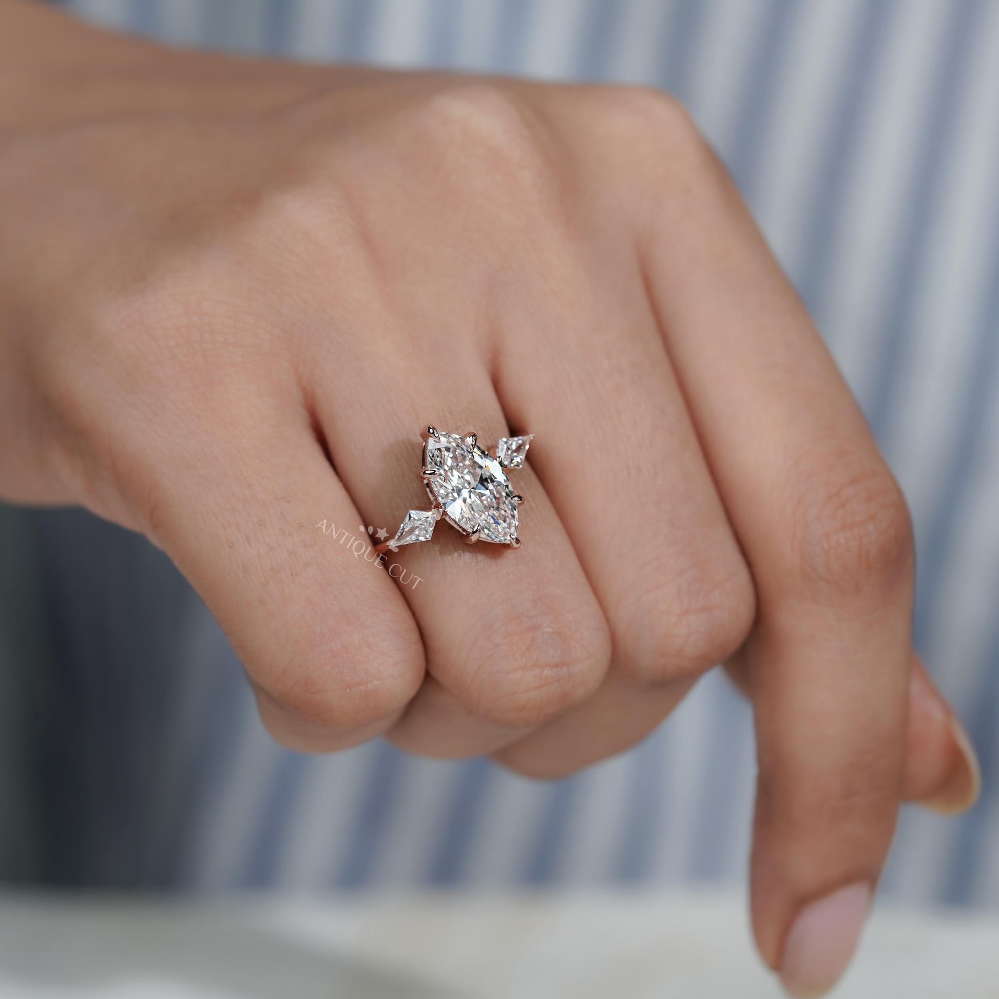 Silver ring with a large diamond on a person's finger against a blurred background