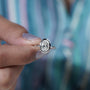 Diamond ring held by a hand with a blurred background