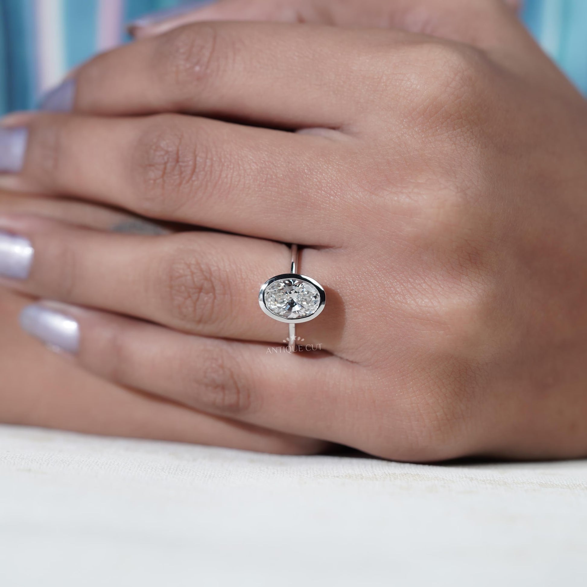 Diamond ring held by a hand with a blurred background
