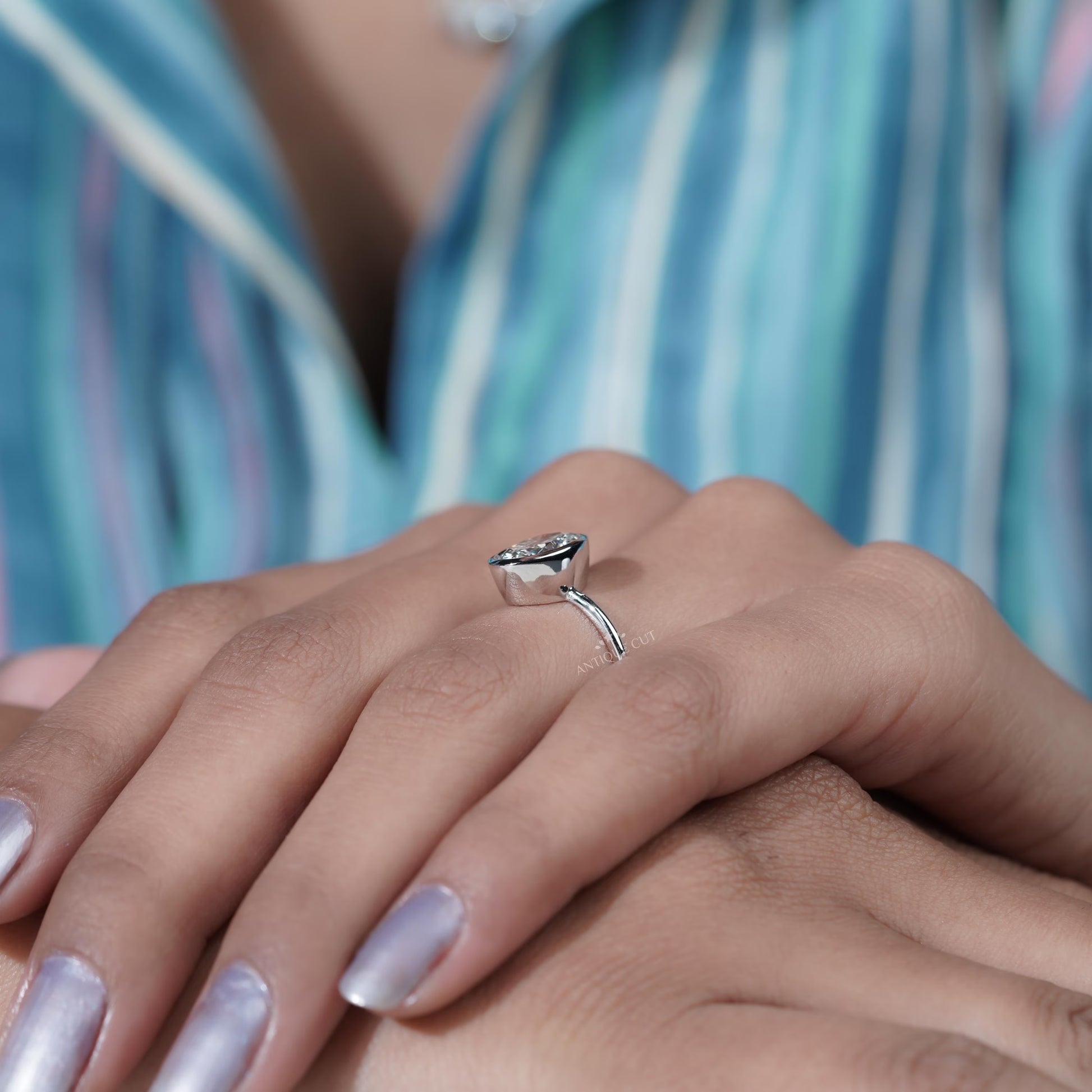 Diamond ring held by a hand with a blurred background