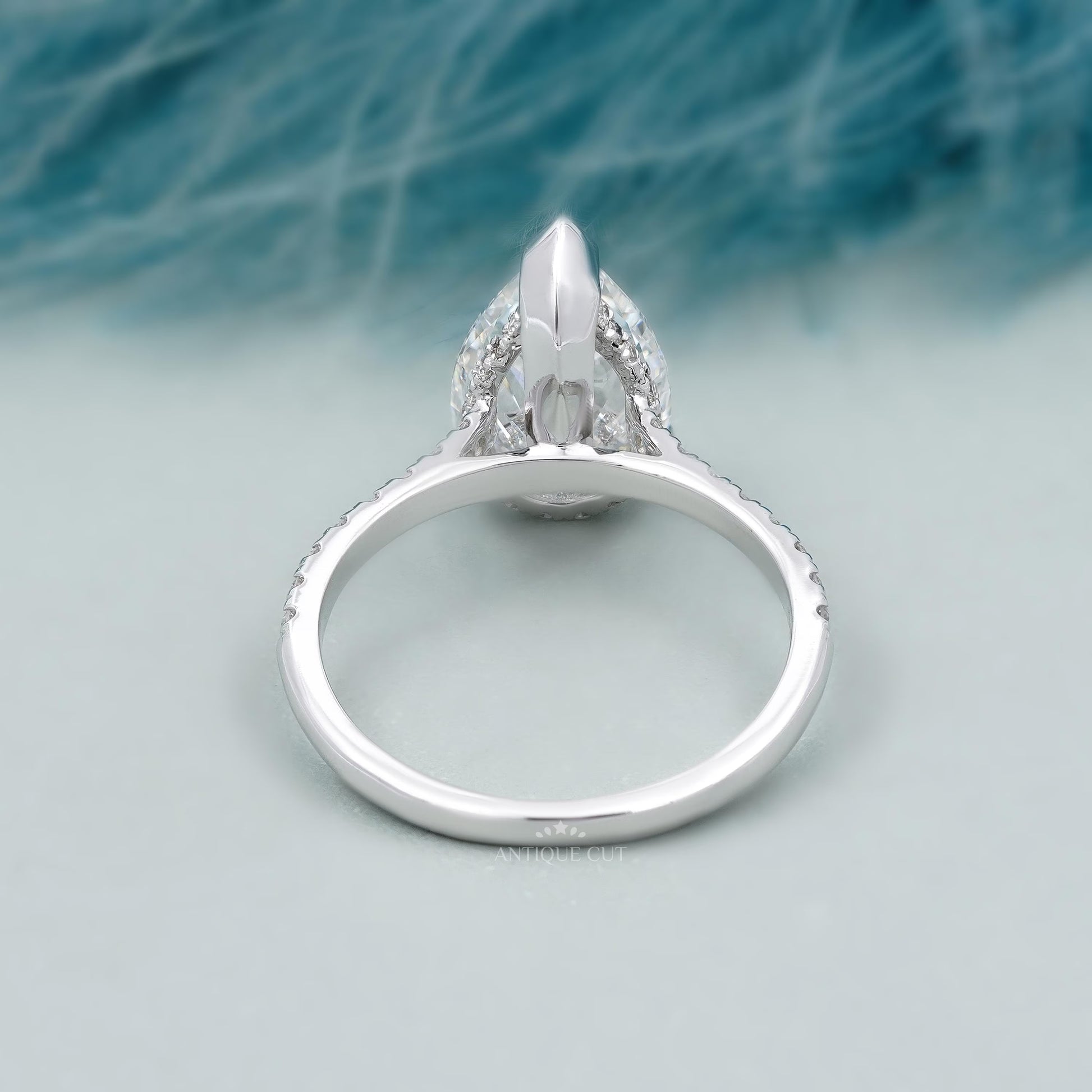 Diamond ring with a pear-shaped center stone on a soft blue background

