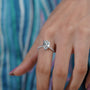 Diamond ring with a pear-shaped center stone on a soft blue background

