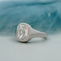 Silver ring with a large diamond on a light blue background