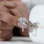 Diamond ring held by a hand with 'AntiqueCut' branding in the background

