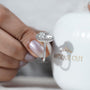 Diamond ring held by a hand with 'AntiqueCut' branding in the background
