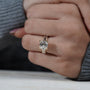 Close-up of a hand wearing a diamond ring on a neutral background

