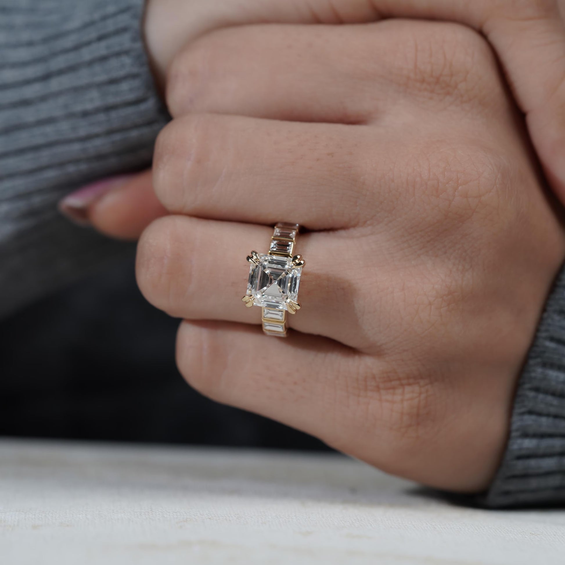 Close-up of a hand wearing a diamond ring on a neutral background

