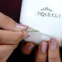 Hand holding a diamond ring with 'Antiquecut' branding in the background