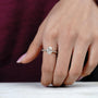Close-up of a hand wearing a diamond ring on a blurred background


