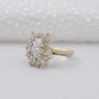 Gold ring with diamond cluster on a light gray background

