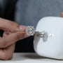 Diamond ring held by a hand with Antiquecut jewelry box in the background

