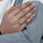 Hand wearing a diamond ring with pink nail polish on a nautral background