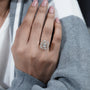 Hand wearing a diamond ring with a blurred background