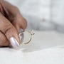 Diamond ring held between fingers with 'AntiqueCut' branding in the background
