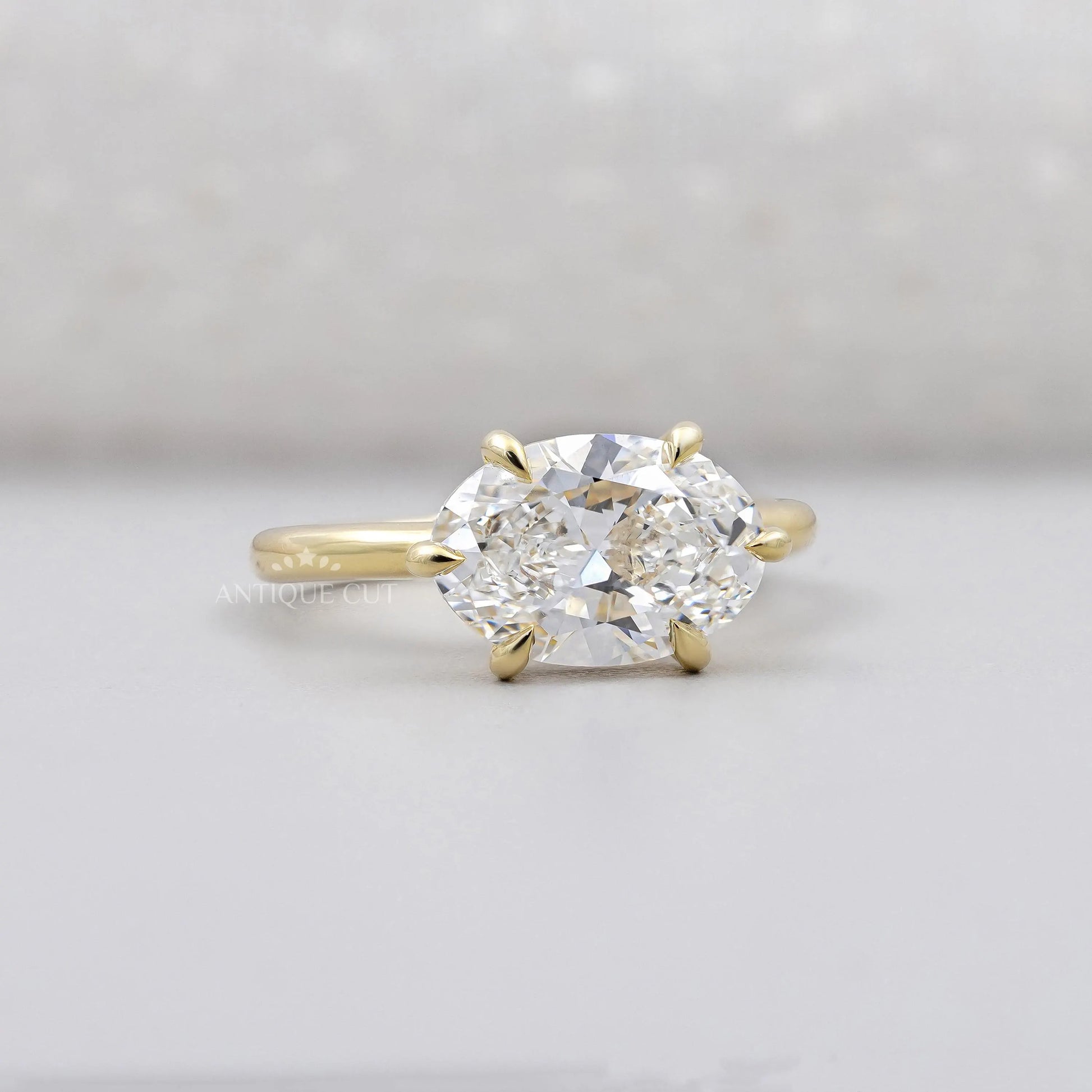 Gold ring with a large diamond on a light gray background

