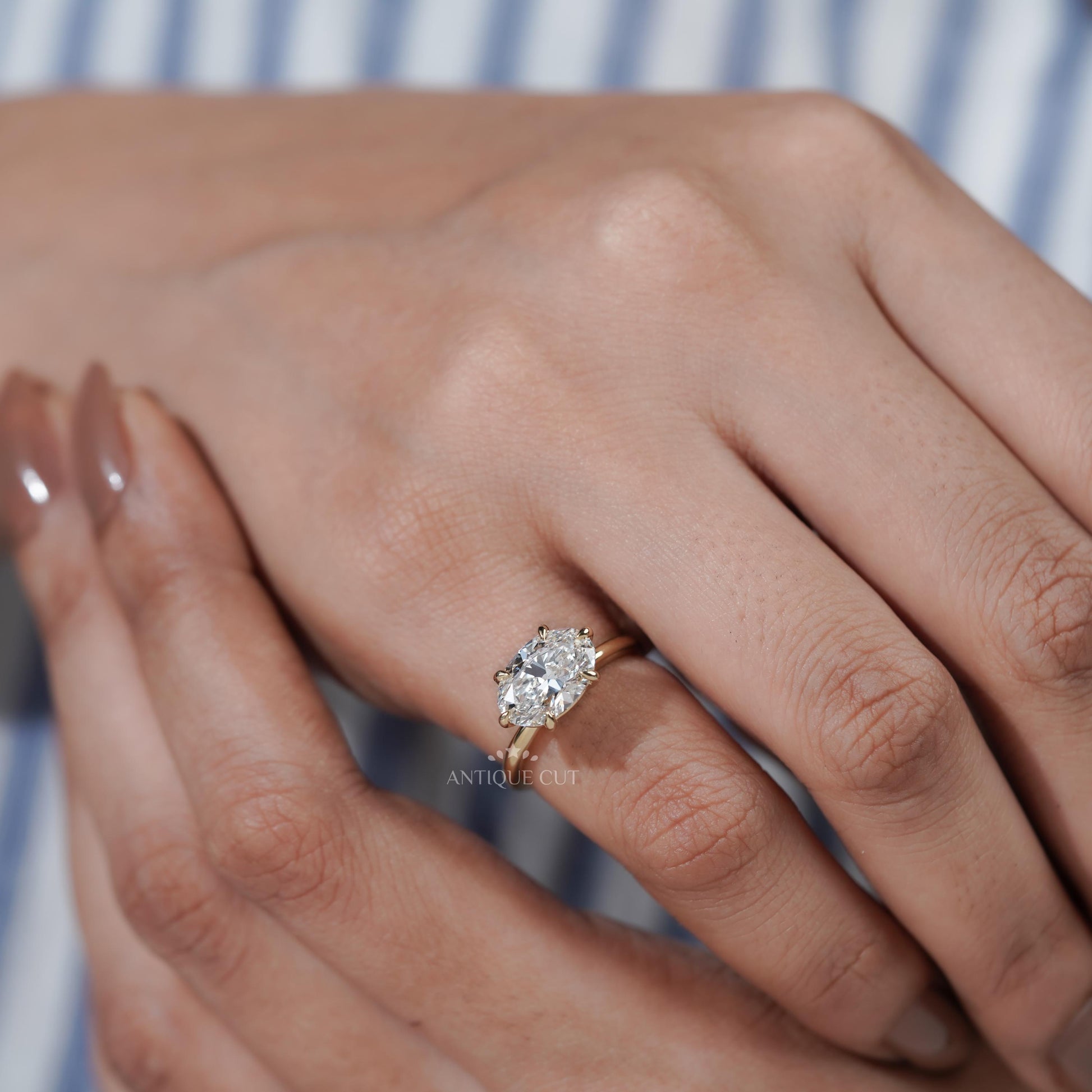 Close-up of a hand wearing a diamond ring with a blurred background

