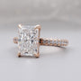 Rose gold ring with a large diamond and smaller diamonds on the band against a gray background

