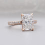 Rose gold ring with a large diamond and smaller diamonds on the band against a gray background

