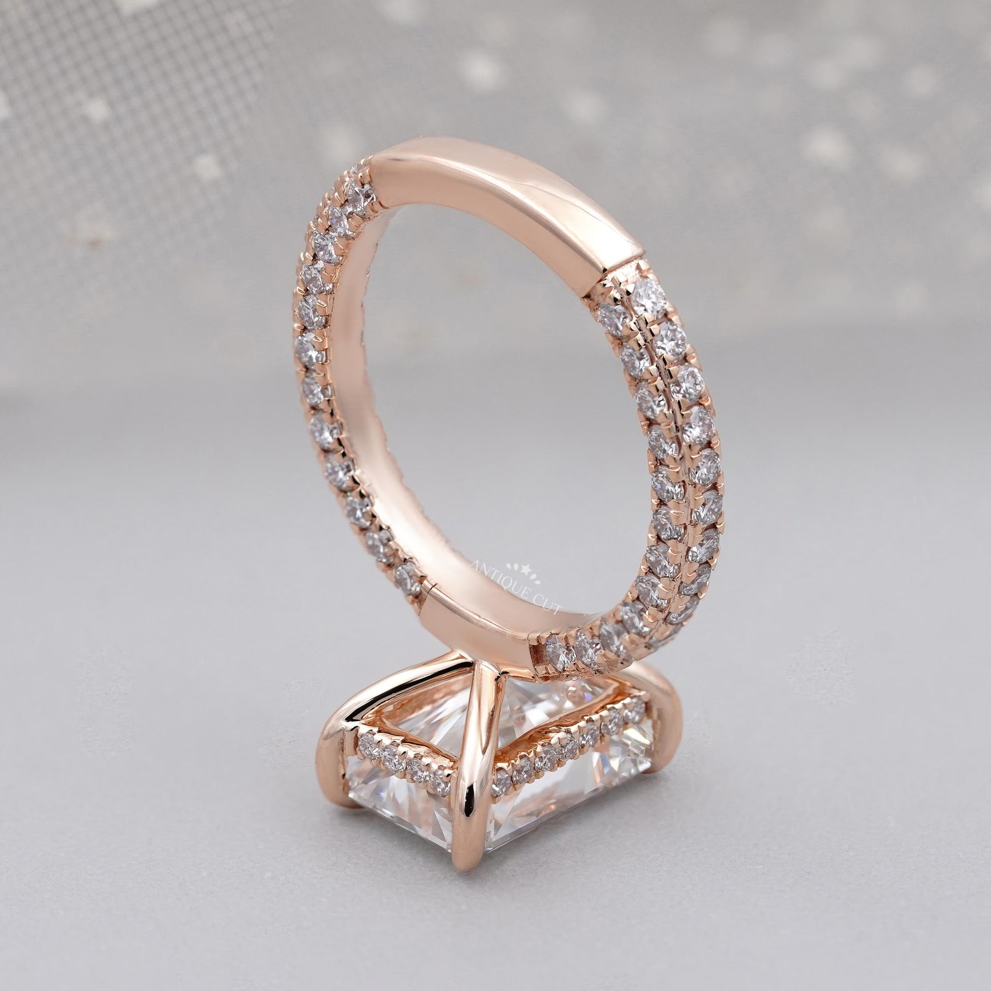 Rose gold ring with diamond accents on a light gray background

