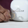 Gold ring with a diamond held by a hand in front of an 'Antique Cut