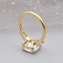 Gold ring with a large central gemstone on a gray background

