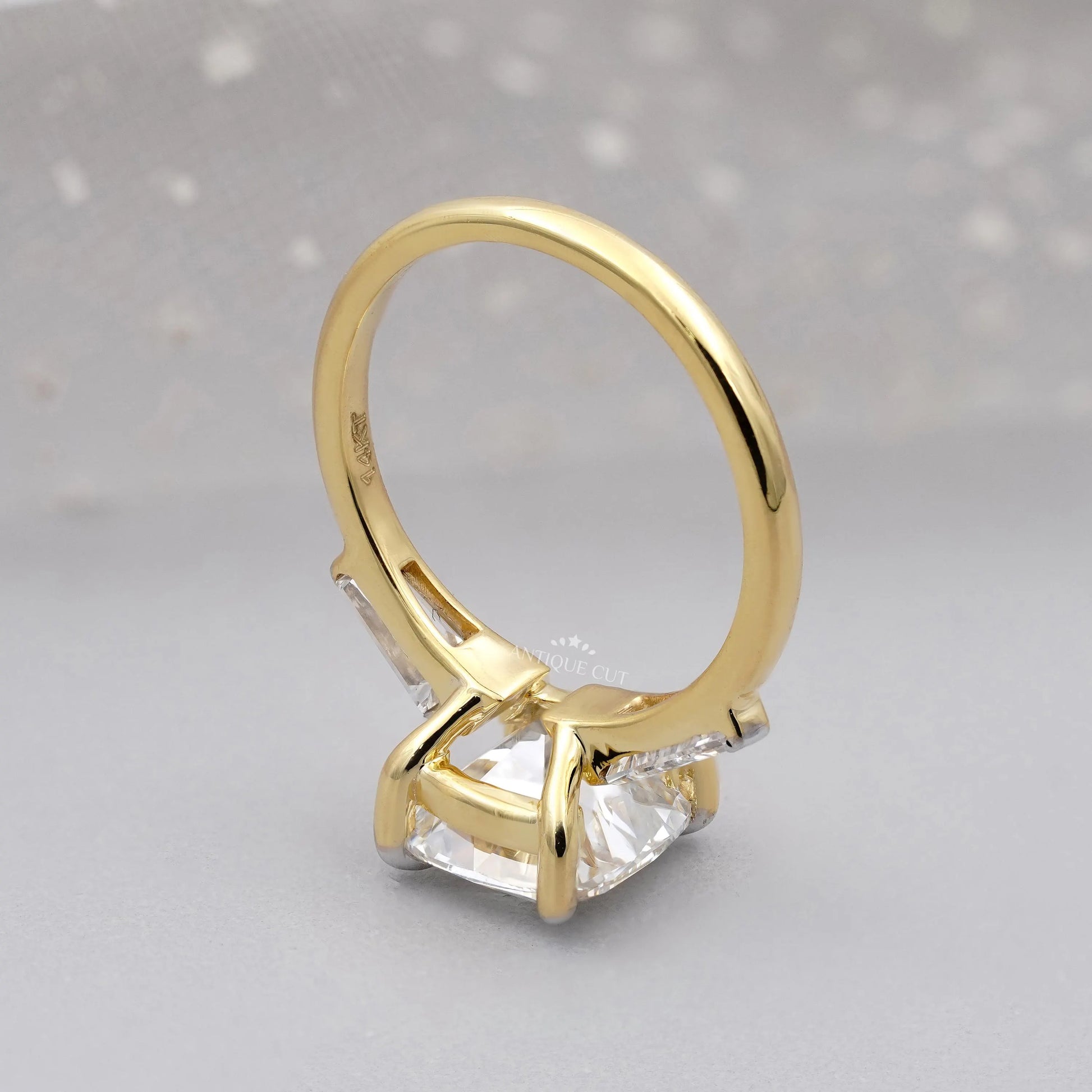 Gold ring with a large central gemstone on a gray background

