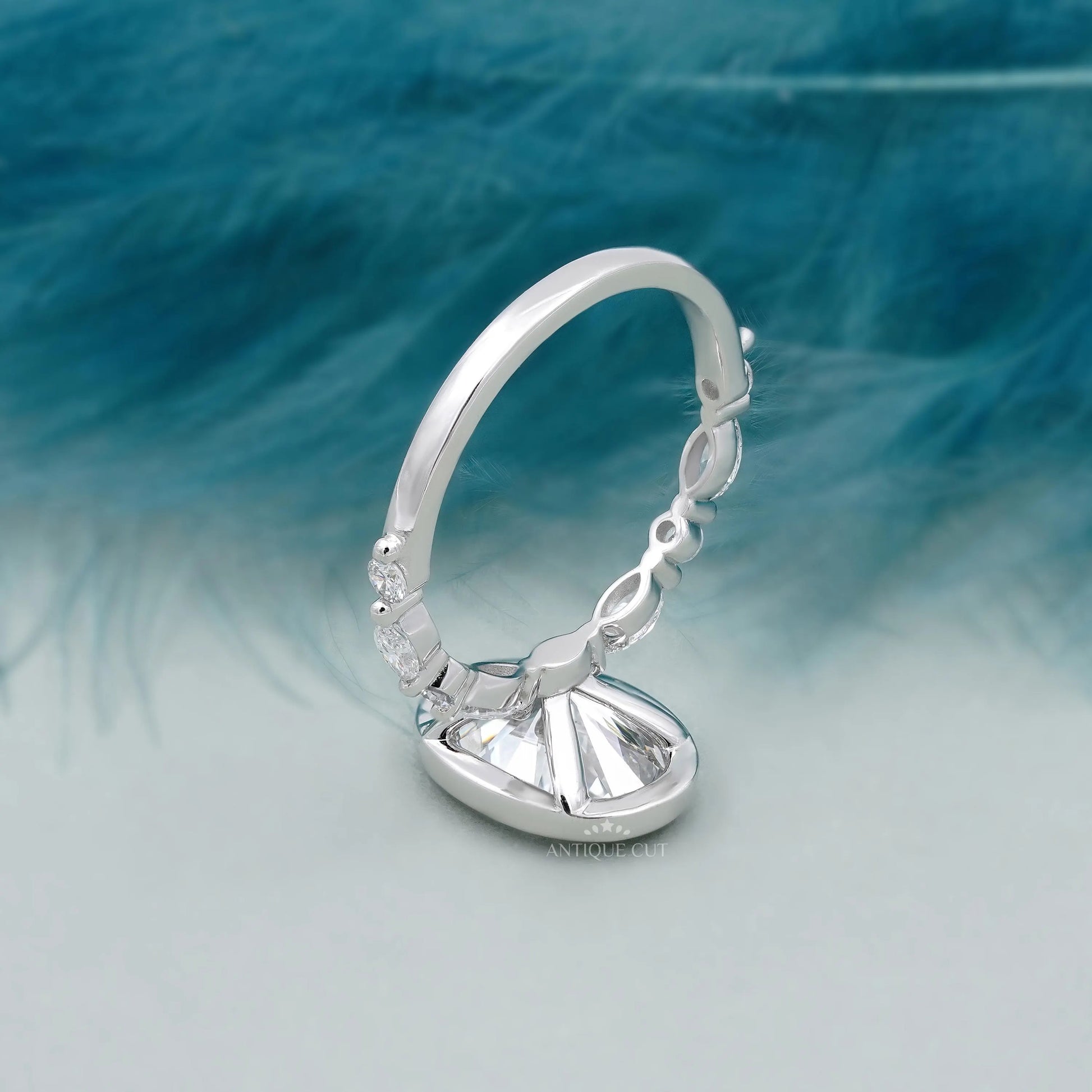 Silver ring with a diamond on a blue feather background

