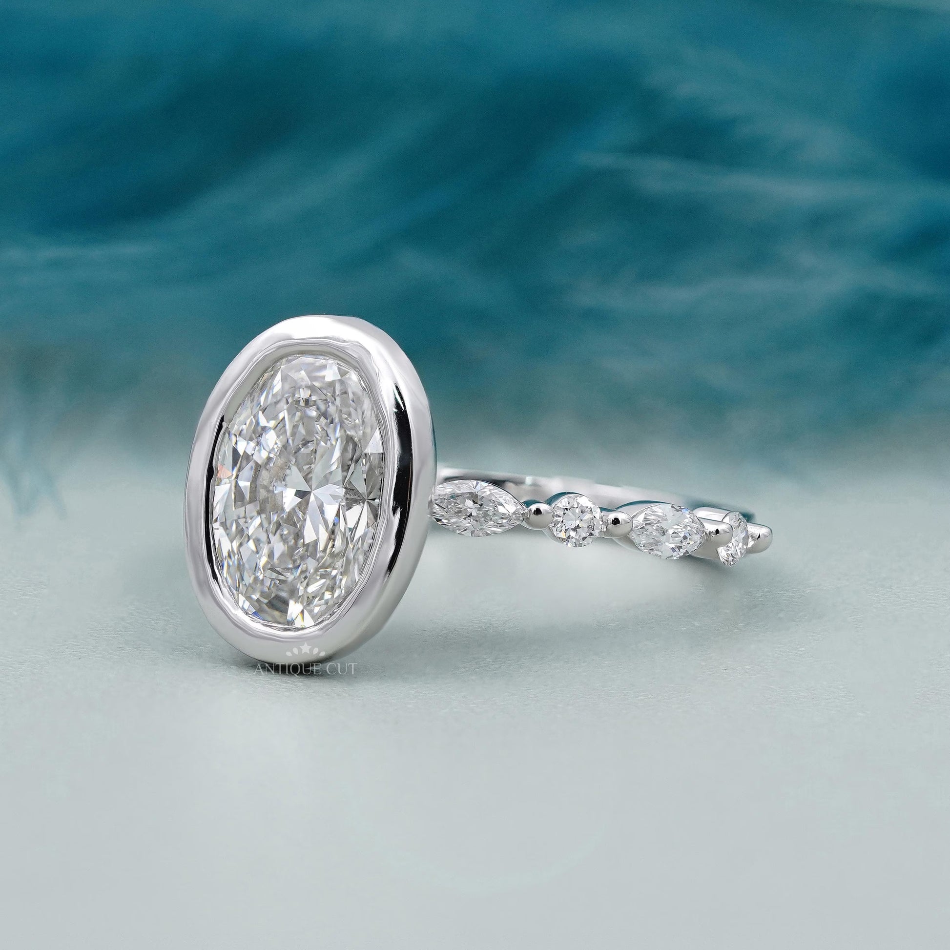 Silver ring with a large diamond and smaller diamonds on a blue and gray gradient background