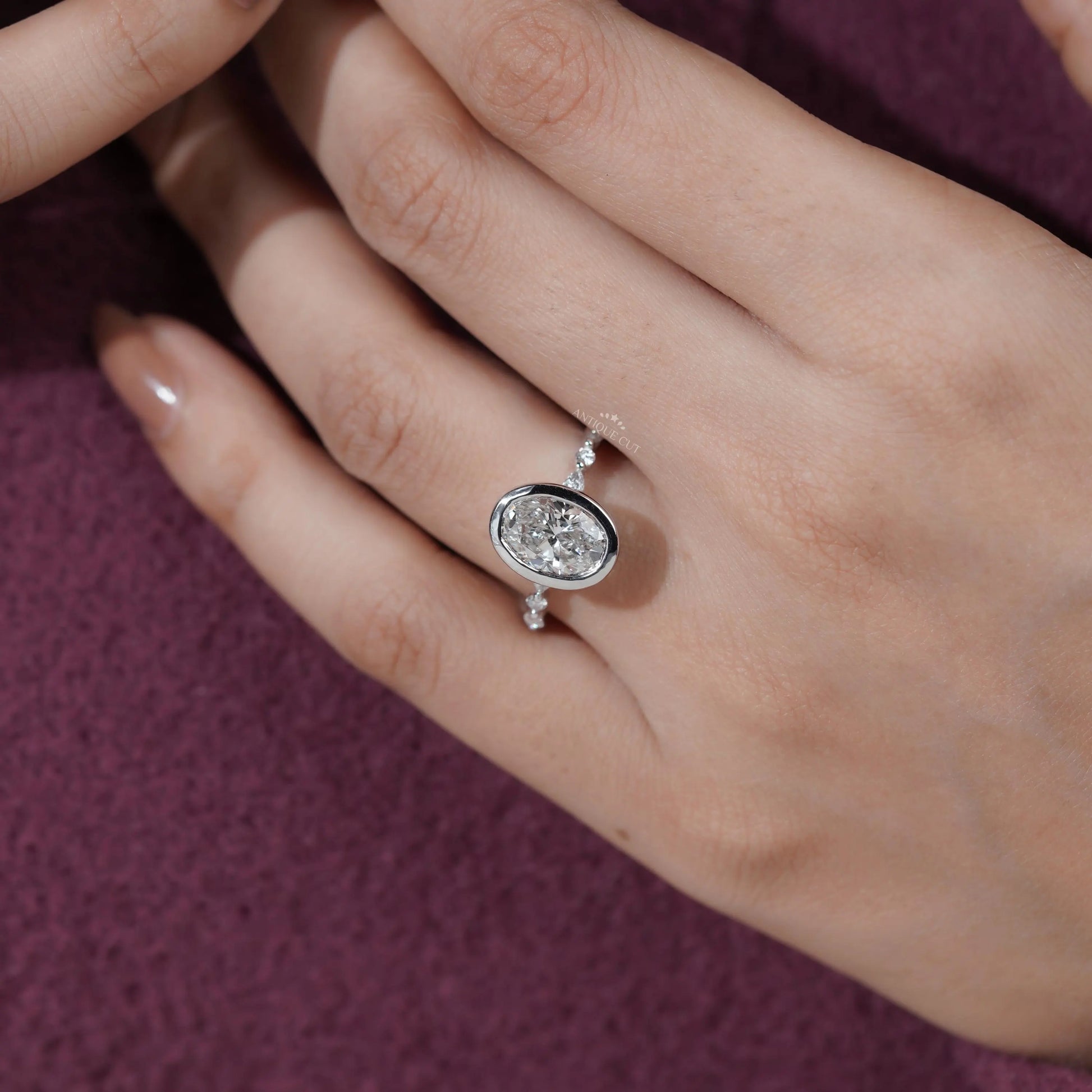 Silver ring with a diamond on a hand against a purple background

