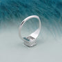 Silver ring with a diamond on a textured blue surface