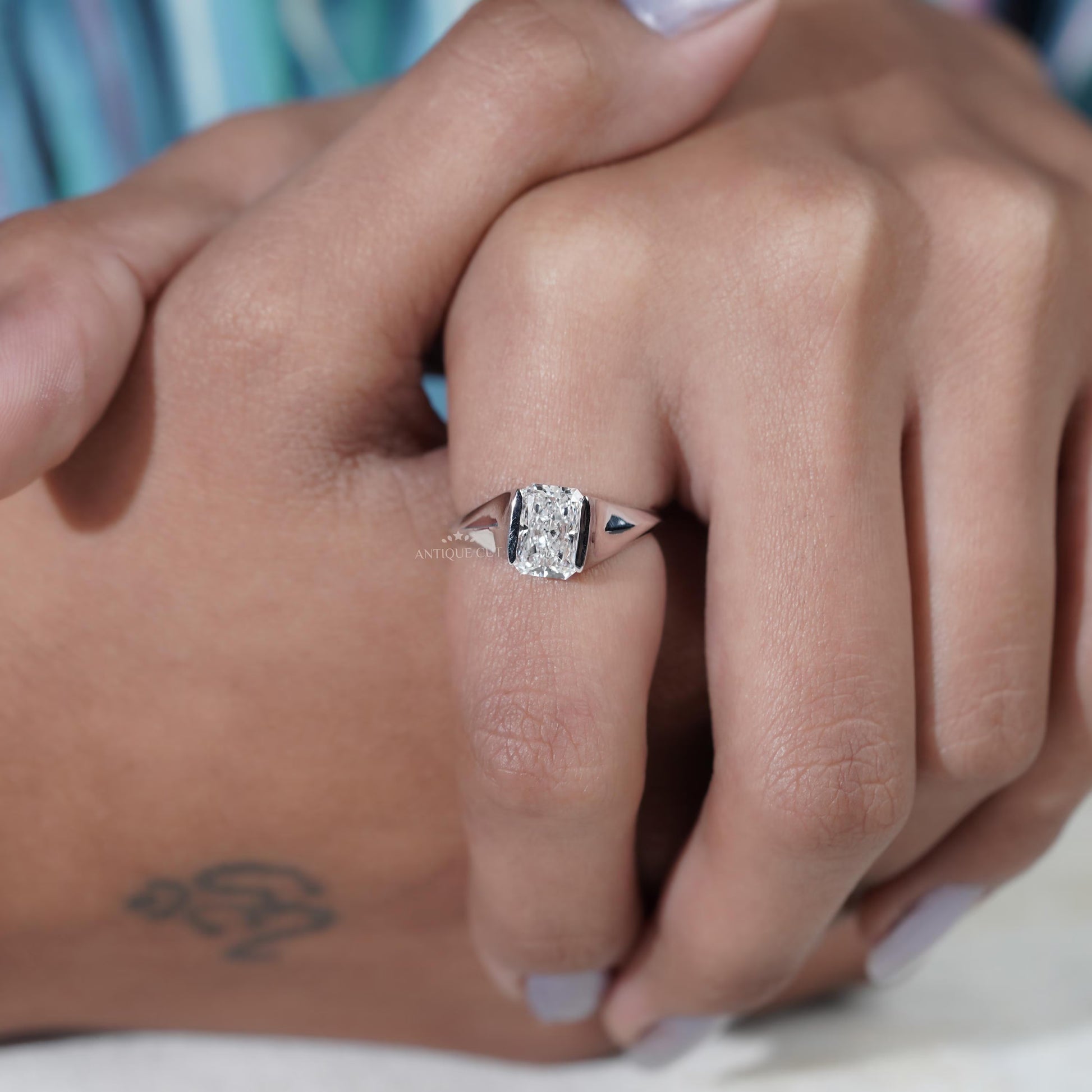 Close-up of a hand wearing a diamond ring with a blurred background

