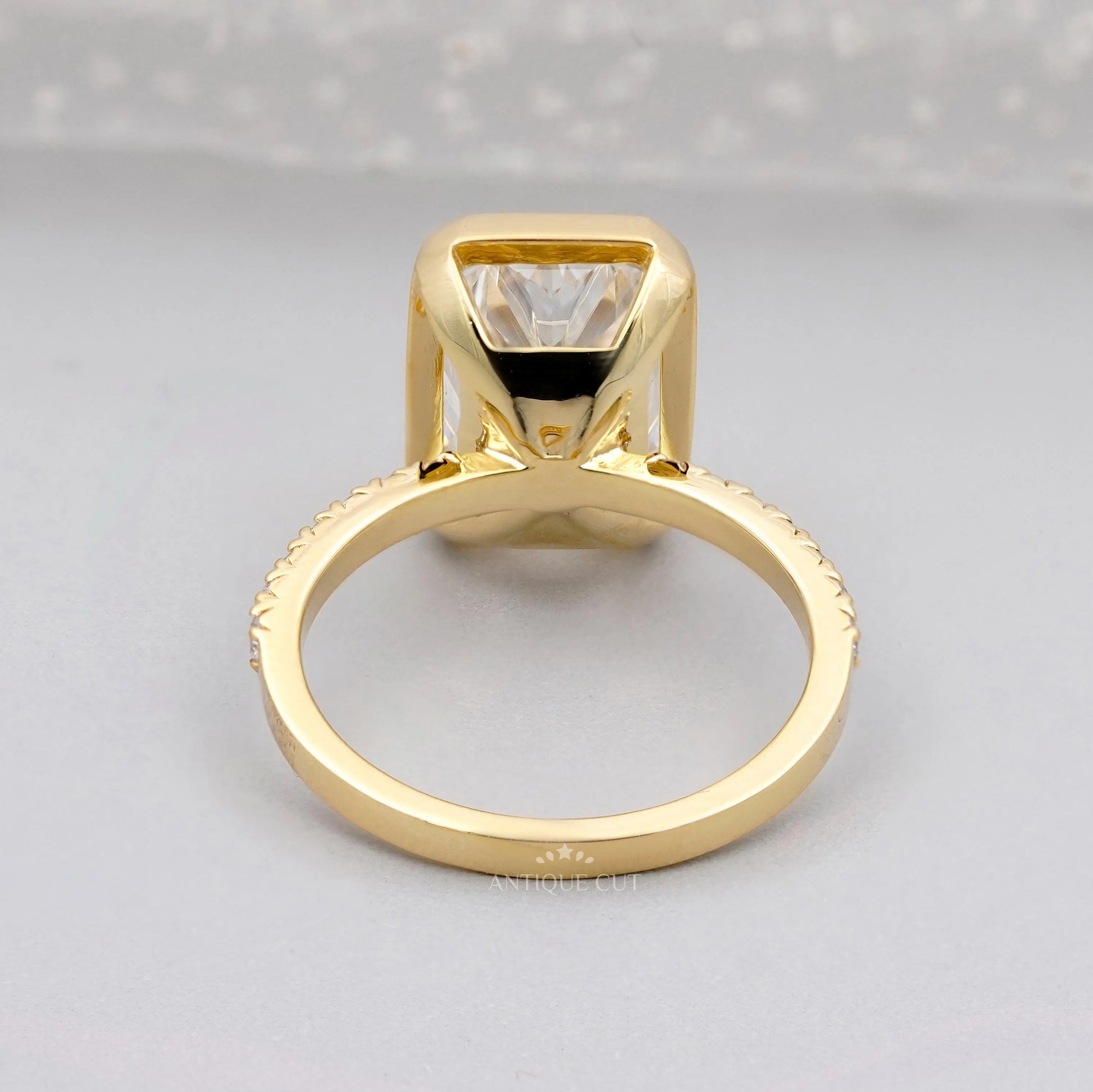 Gold ring with a large diamond and smaller diamonds on the band against a gray background