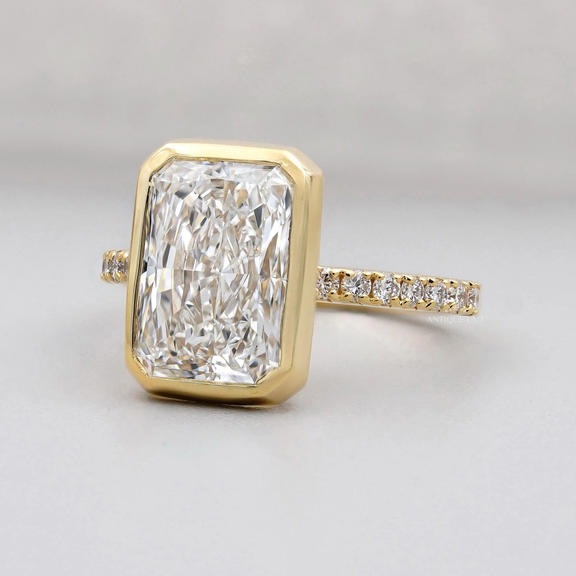 Gold ring with a large diamond and smaller diamonds on the band against a gray background