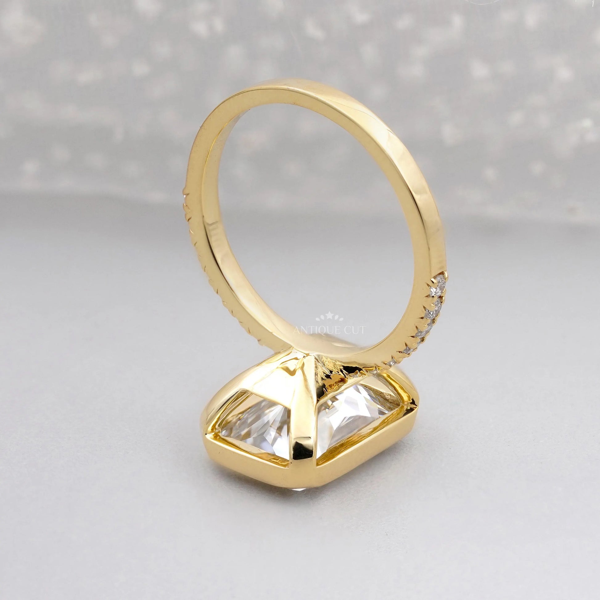 Gold ring with a large diamond and smaller diamonds on the band against a gray background