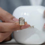 Gold ring with a large diamond held by a hand against a blurred background

