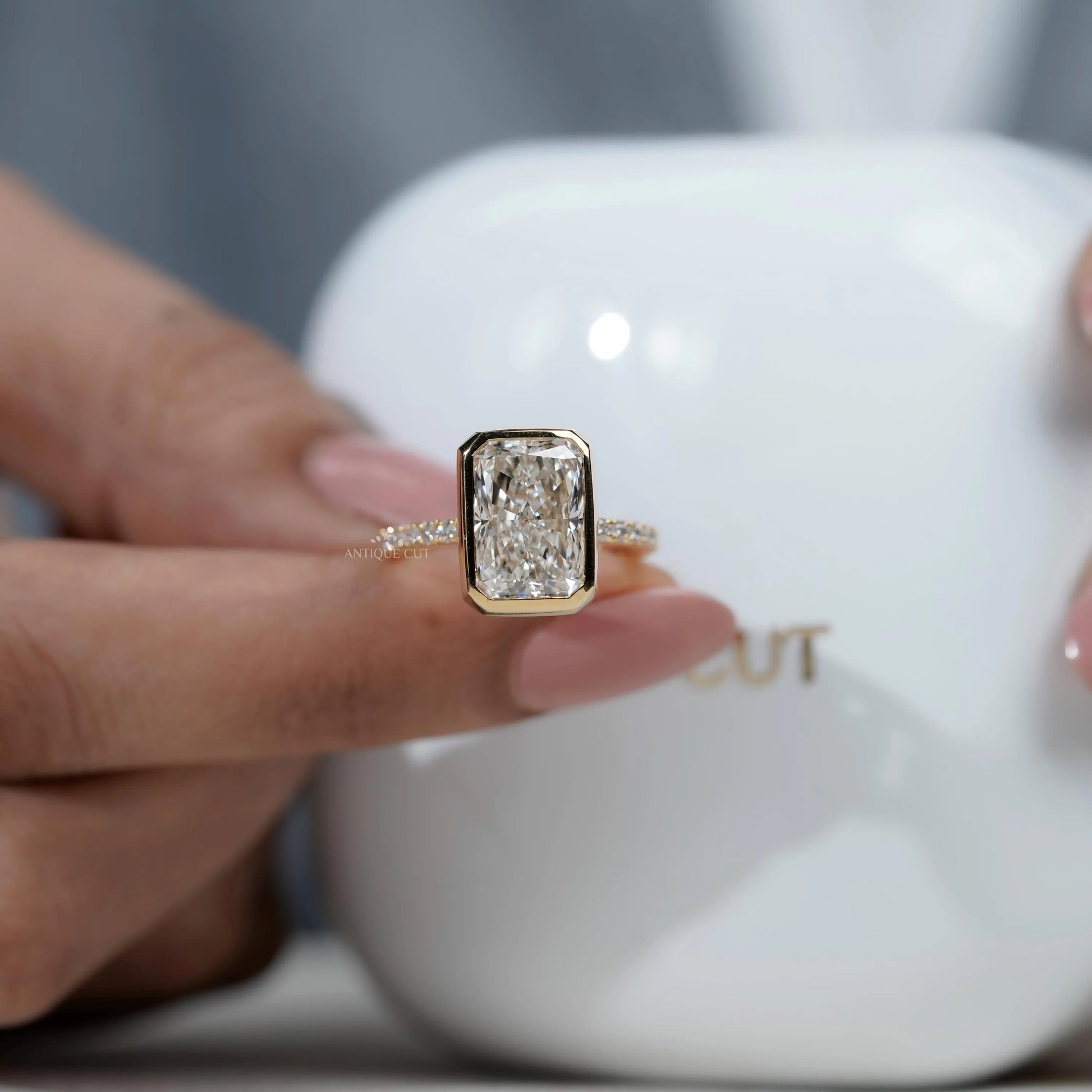 Gold ring with a large diamond held by a hand against a blurred background

