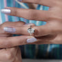 Diamond ring held by a hand with a blurred background