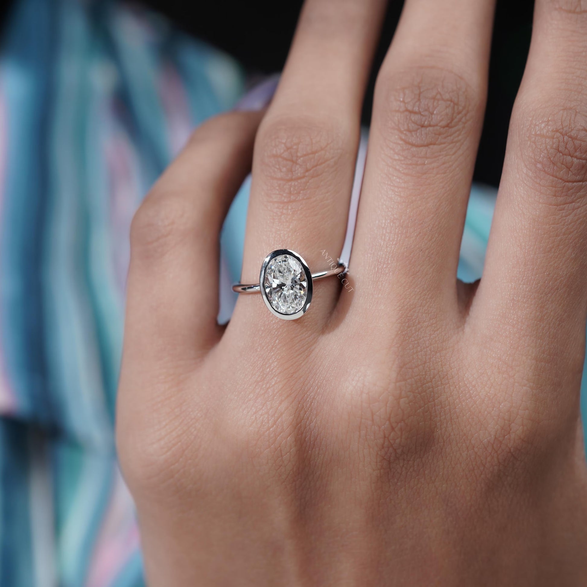 Diamond ring held by a hand with a blurred background