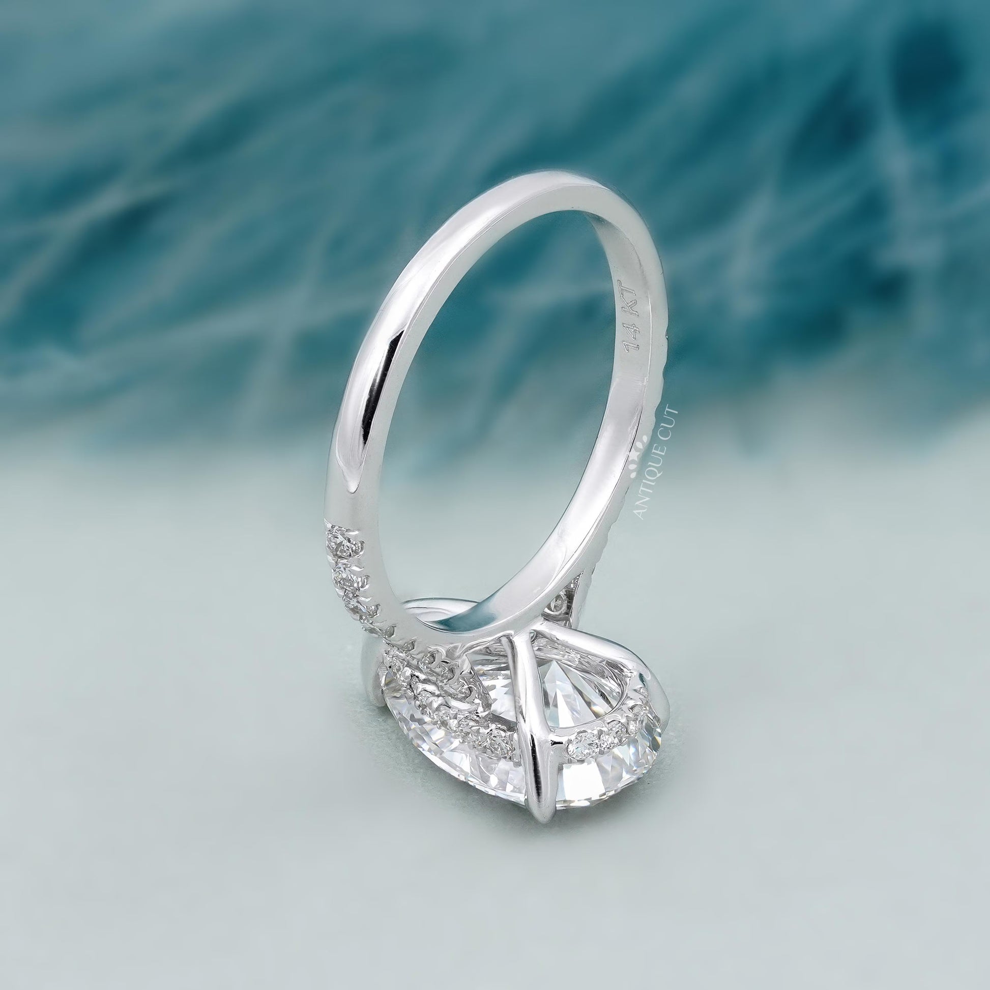 Diamond ring with a pear-shaped center stone on a soft blue background

