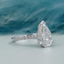 Diamond ring with a pear-shaped center stone on a soft blue background

