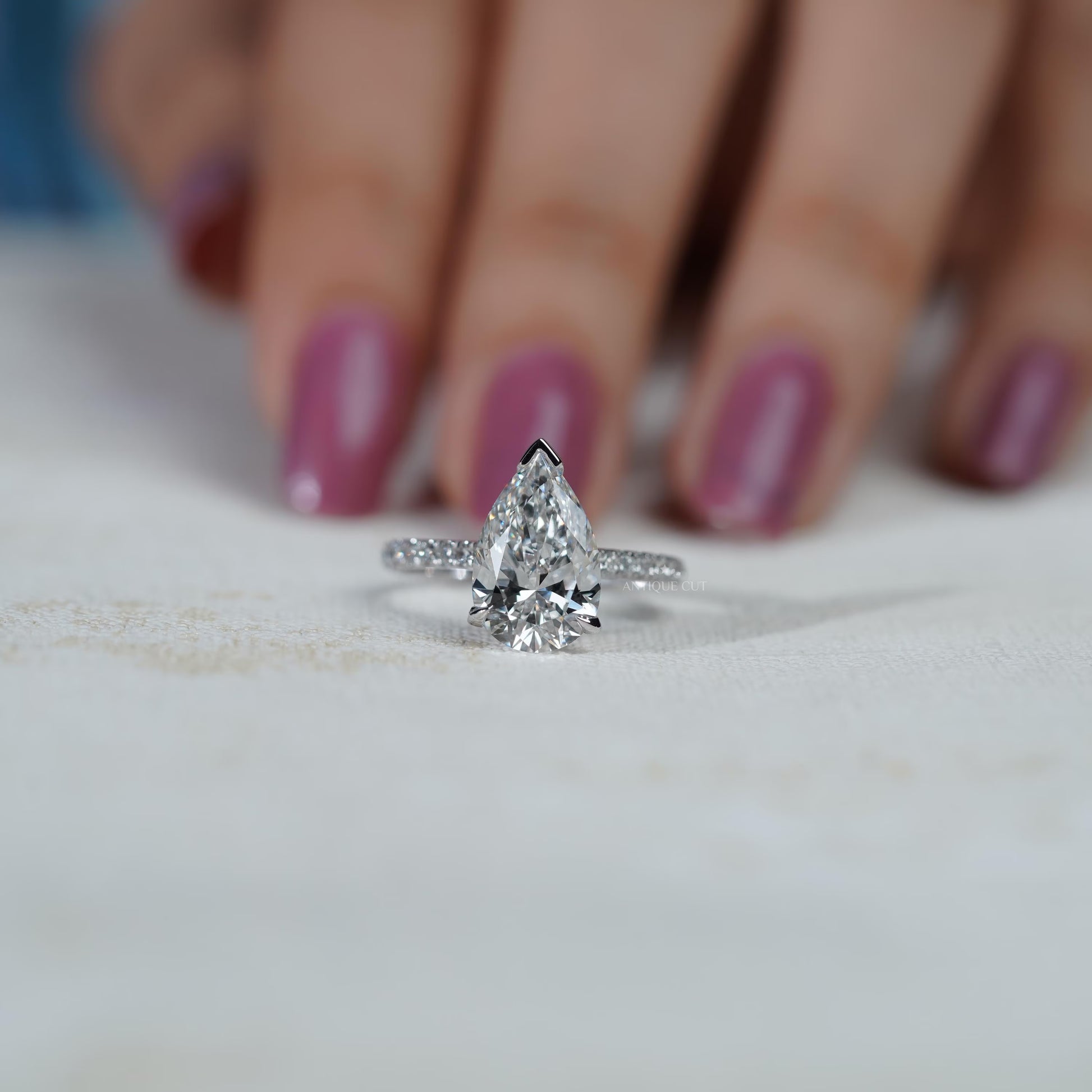 Diamond ring with a pear-shaped center stone on a soft blue background

