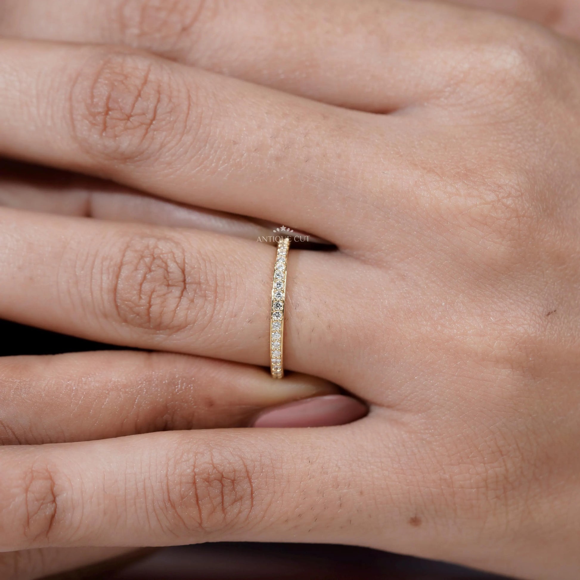 Close-up of a hand wearing a gold ring with small diamonds.