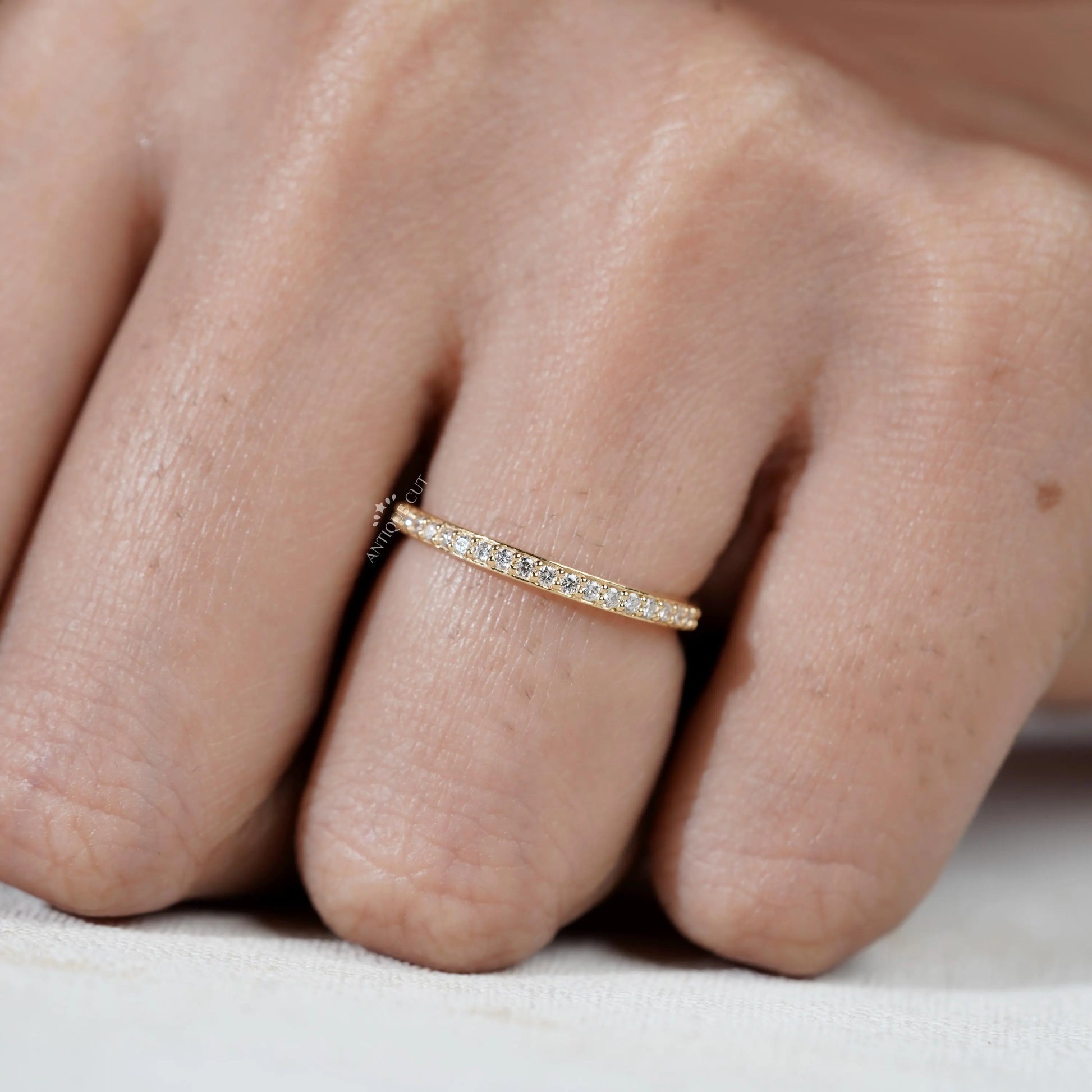 Close-up of a hand wearing a gold ring with small diamonds