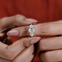 Diamond earring held between fingers against a red background

