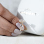 Diamond ring held between fingers with 'AntiqueCut' branding in the background
