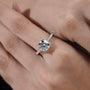 Close-up of a hand wearing a diamond ring with a blurred background