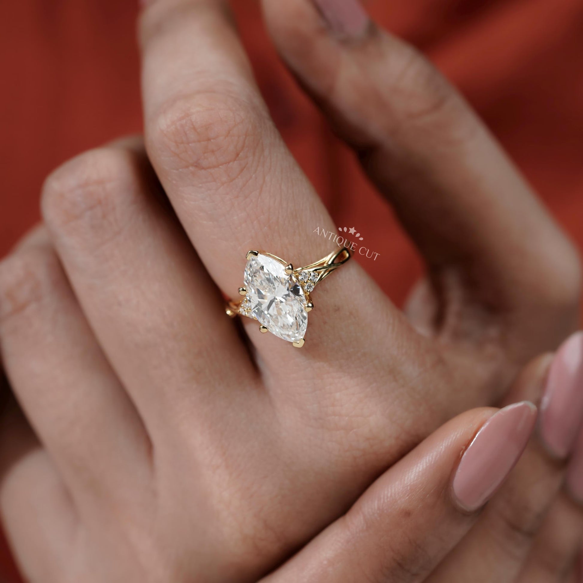 Gold ring with a large diamond on a hand against a red background