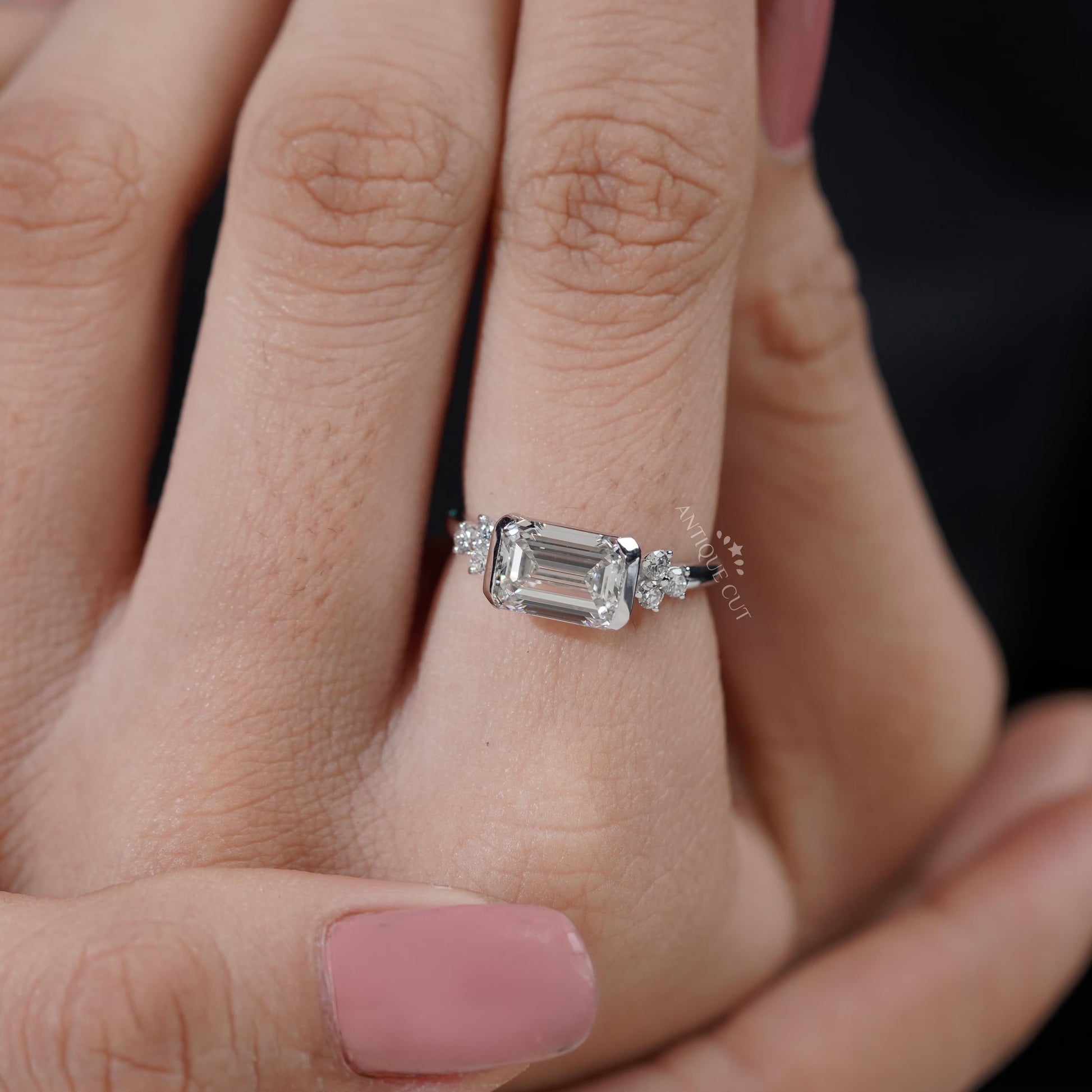 Bezel set emerald cut engagement ring in white gold
