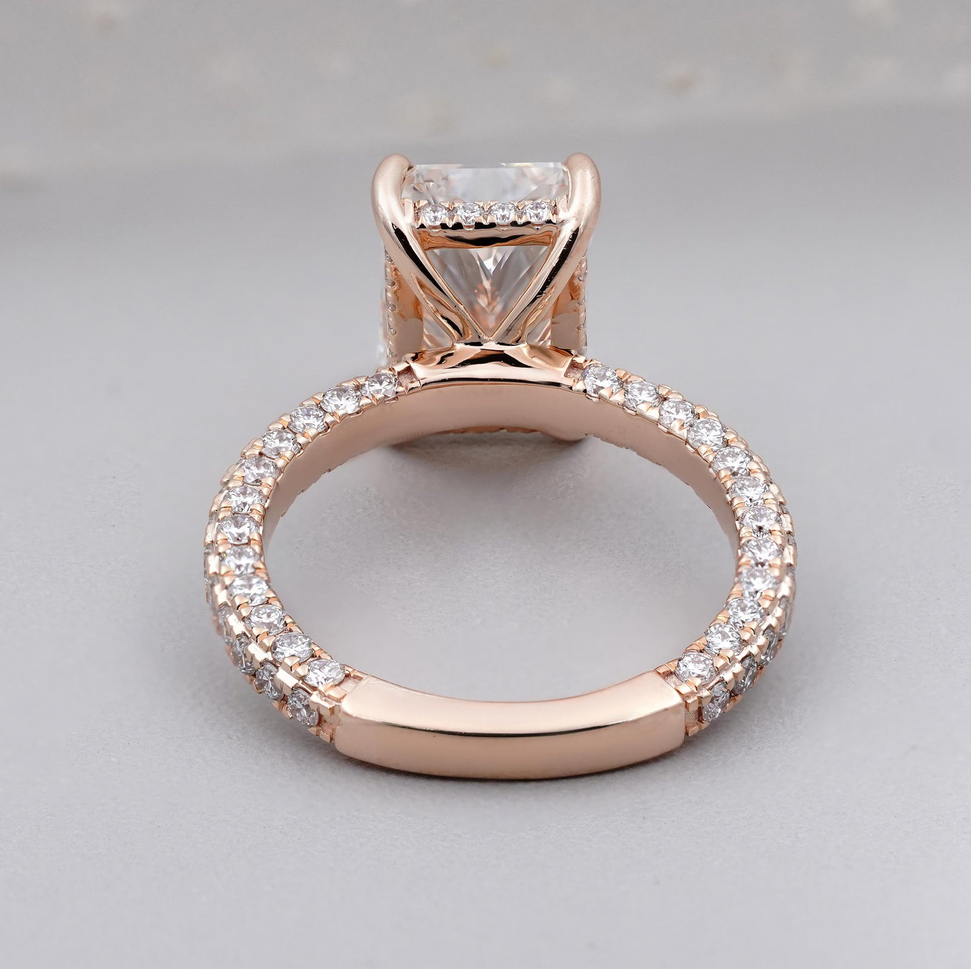 Rose gold ring with diamond accents on a light gray background

