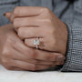 Close-up of a hand wearing a diamond ring with a blurred background

